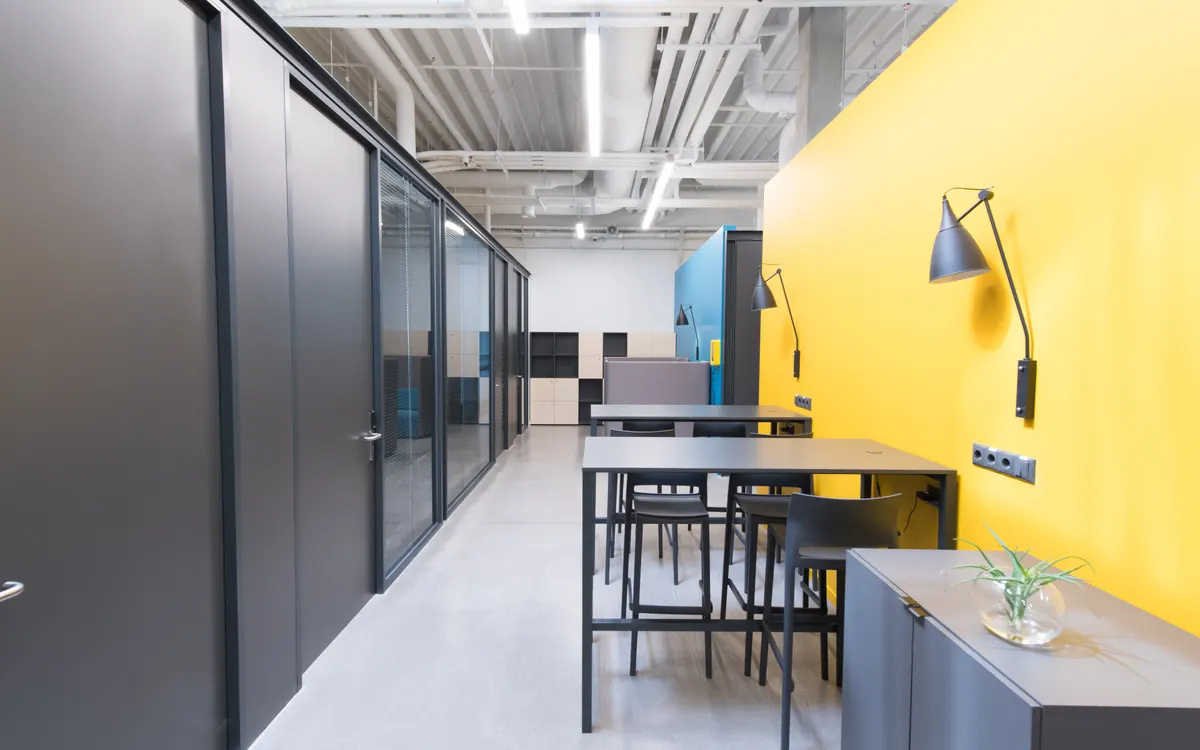 Modern office interior with charcoal partitions and a yellow accent wall