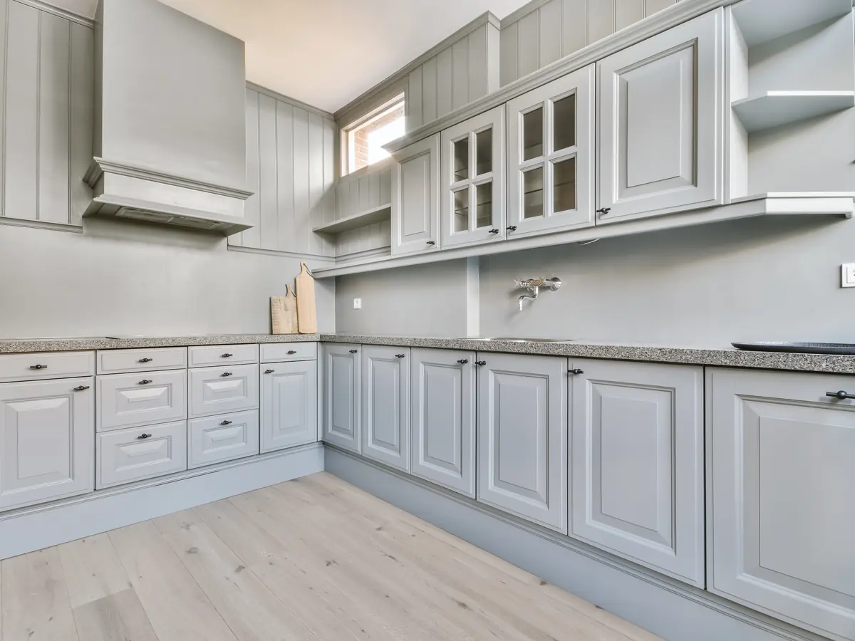 Light gray painted raised-panel kitchen cabinets with glass-front uppers