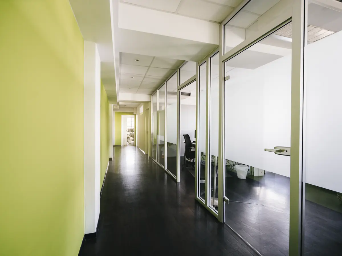 Office corridor with freshly painted green walls and glass partitions