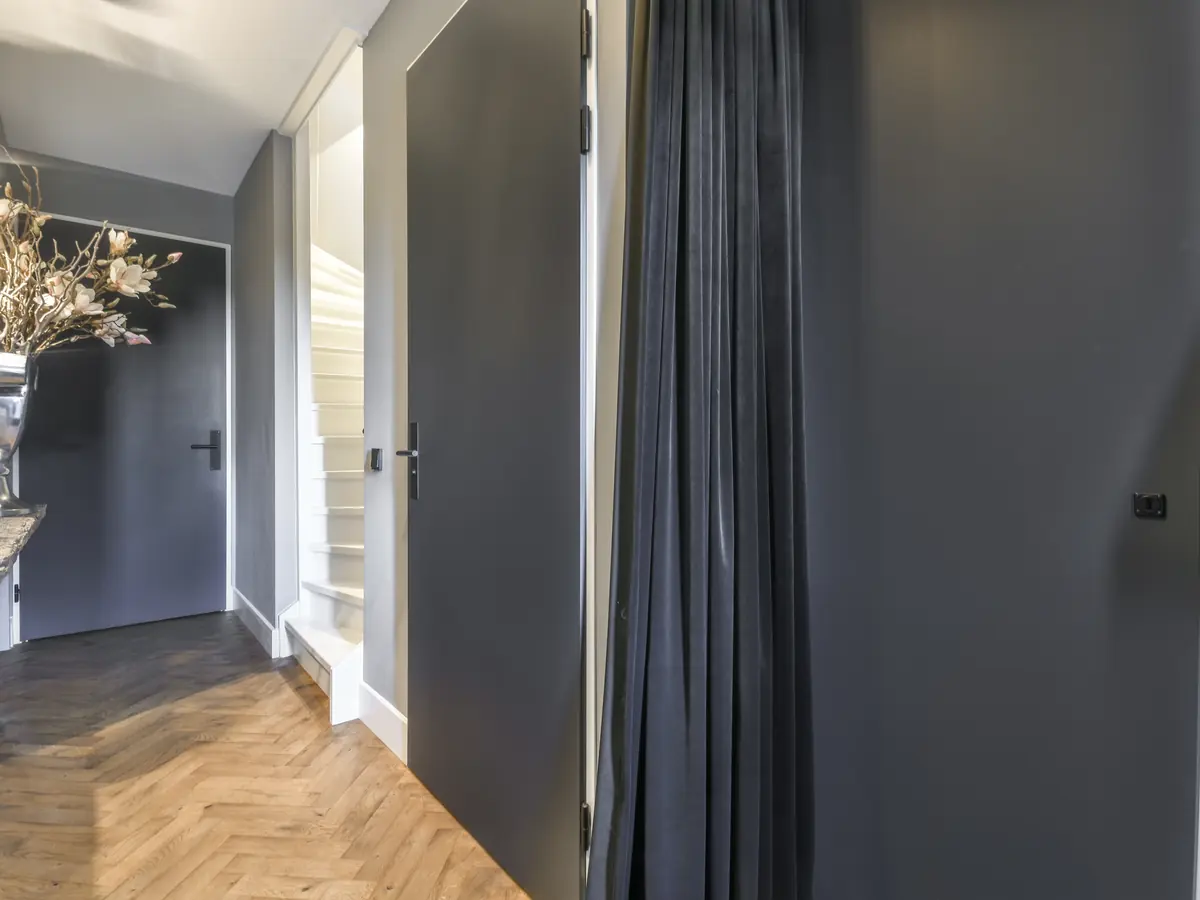 Hallway with white painted doors and trim beside a wood staircase
