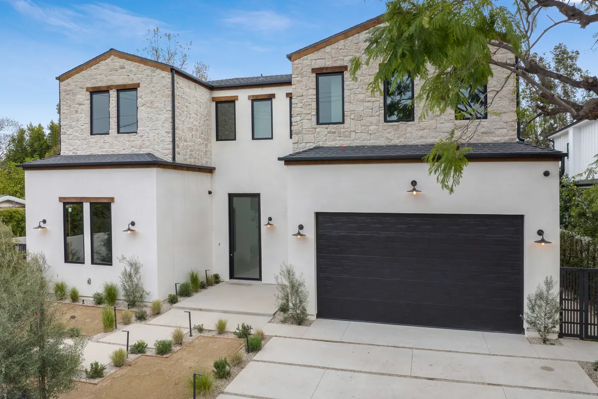 Two-story Houston home with white stucco, stone gables and black trim, exterior house painting by Blue Oak Painting Company