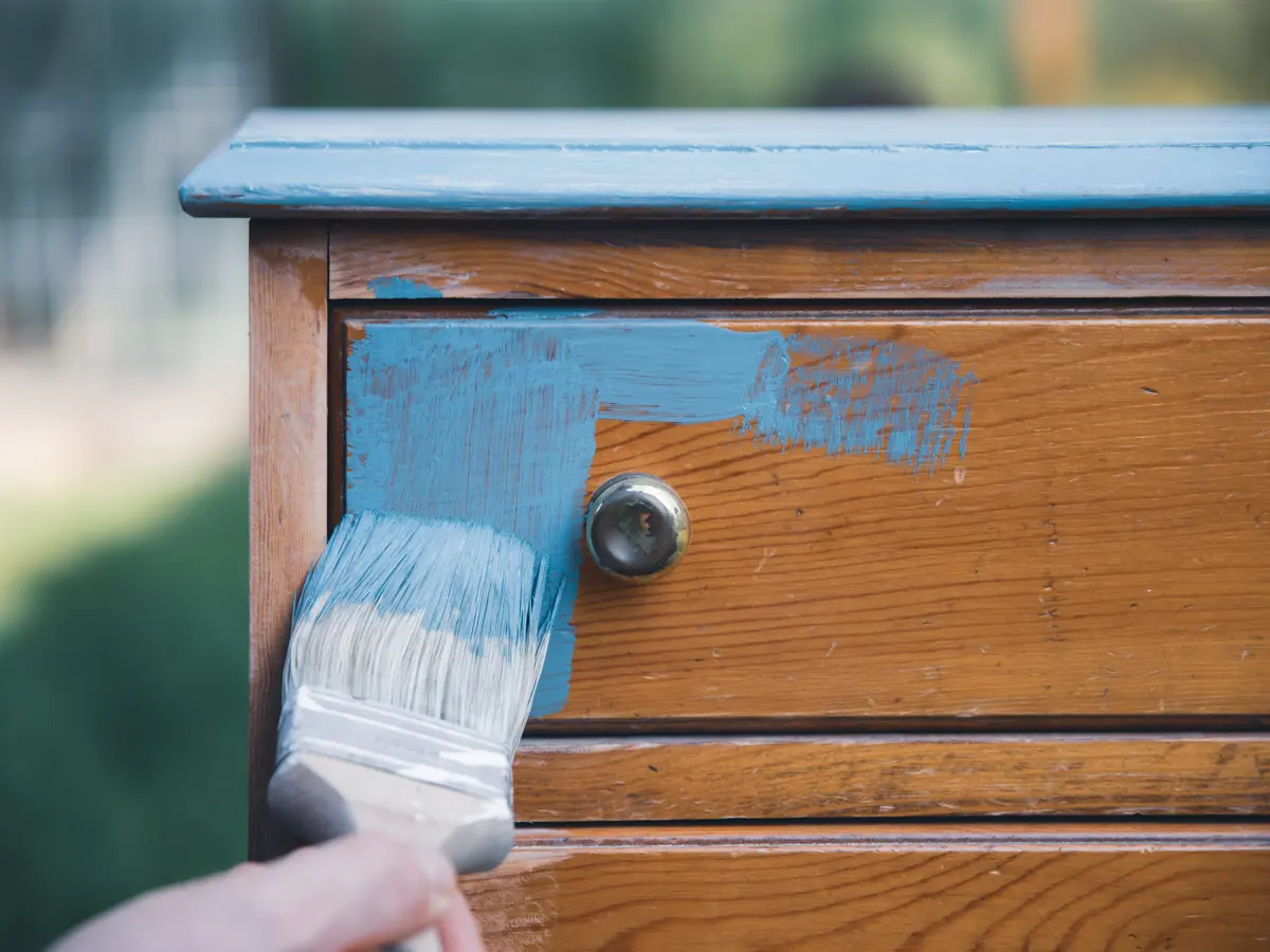 Blue chalk paint going onto an oak dresser drawer front