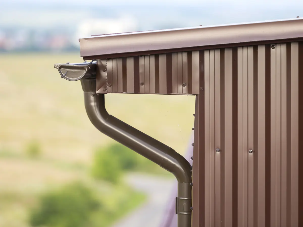 Brown painted gutter and downspout on a metal sided home