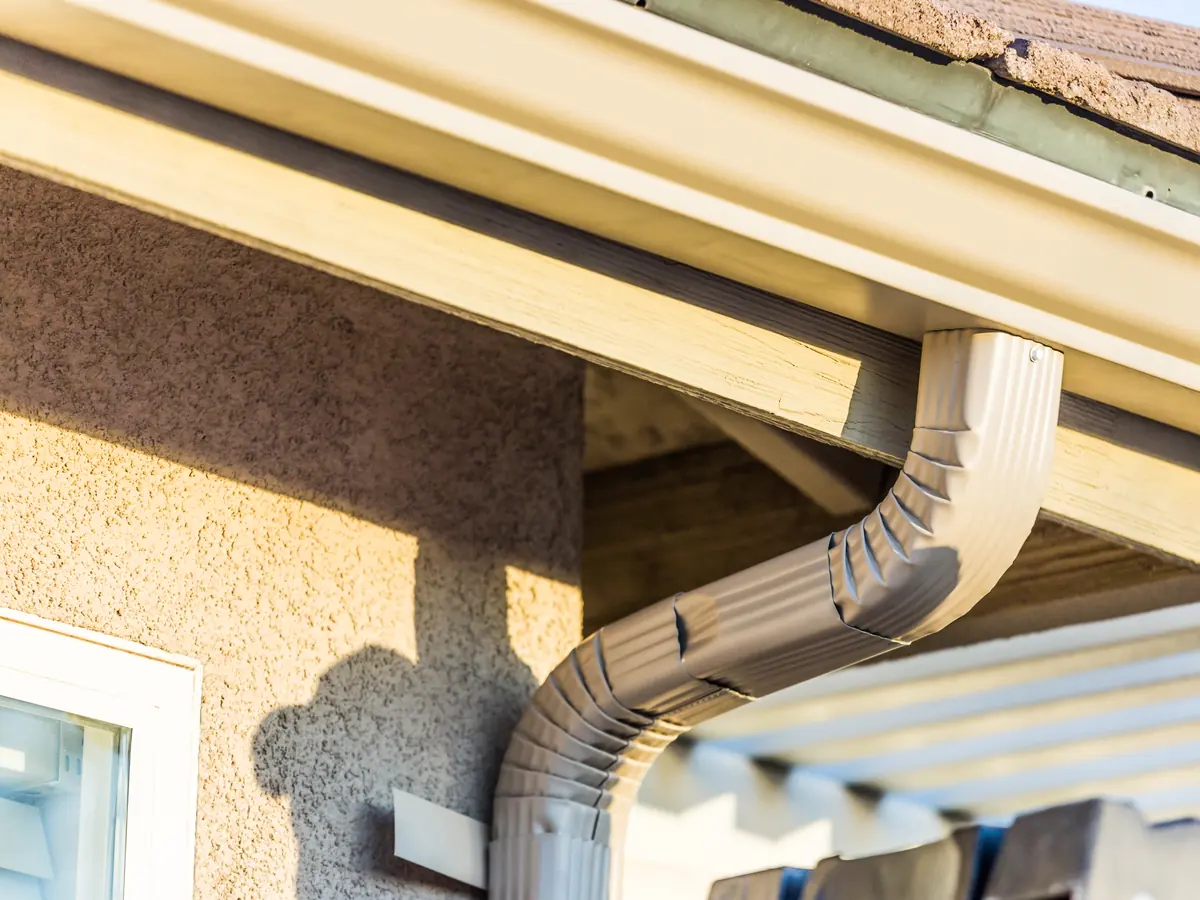 Seamless gutter and downspout on a stucco home in afternoon sun