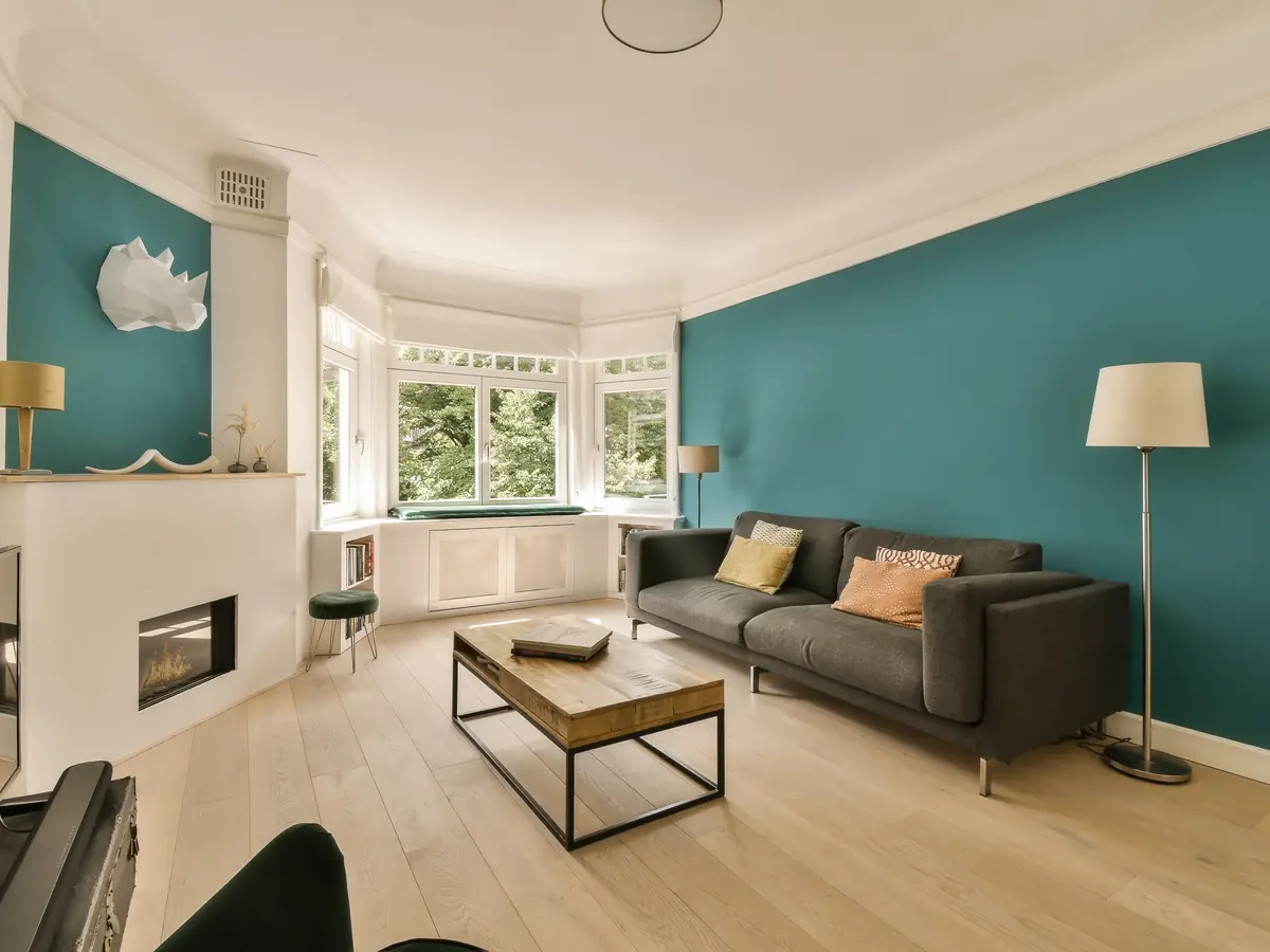 Living room with a deep teal accent wall and crisp white trim