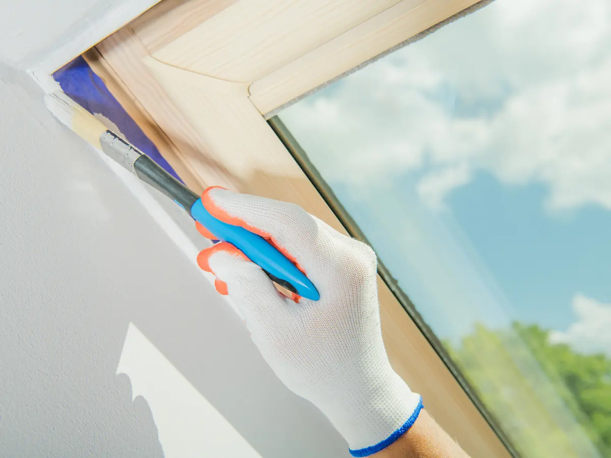 Brush cutting in the corner of a skylight frame with painter's tape