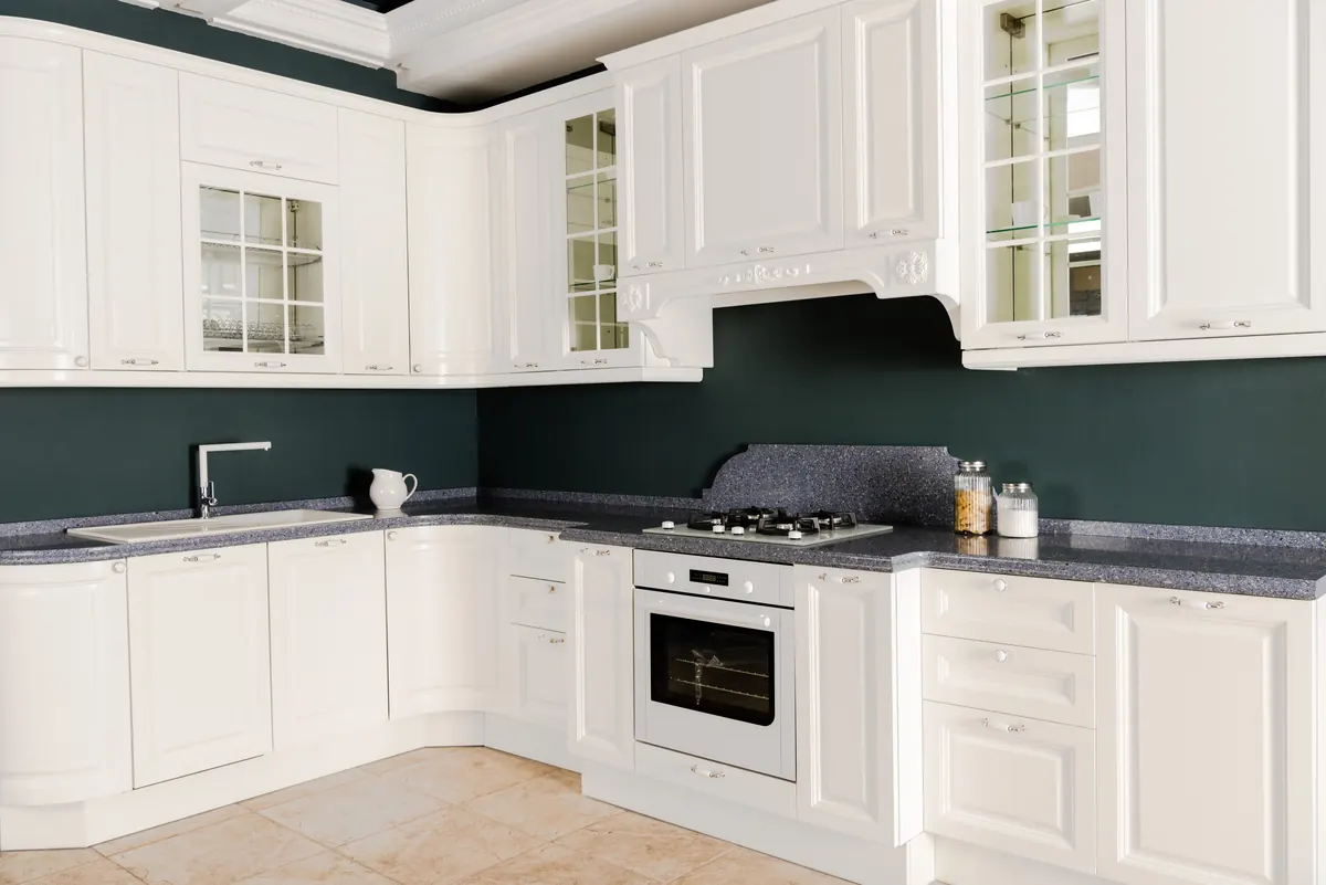 White painted raised-panel kitchen cabinets with glass-front uppers, kitchen cabinet painting by Blue Oak Painting Company in Houston, TX