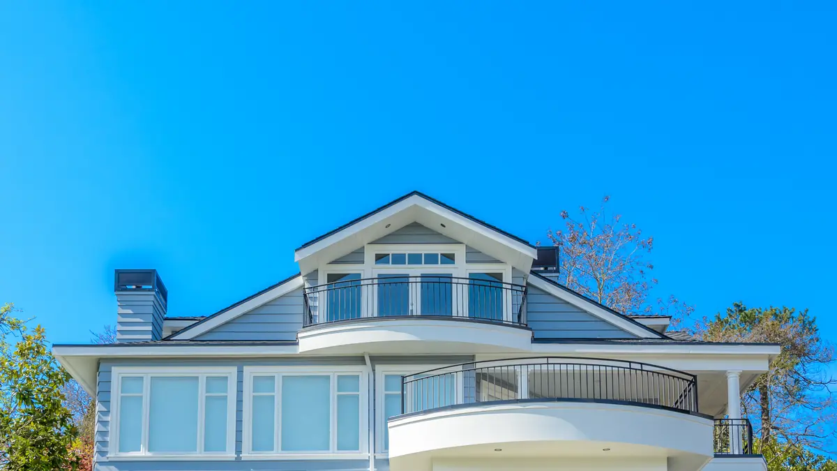 Freshly painted blue and white two-story home with balconies under a clear sky in Sugar Land, TX