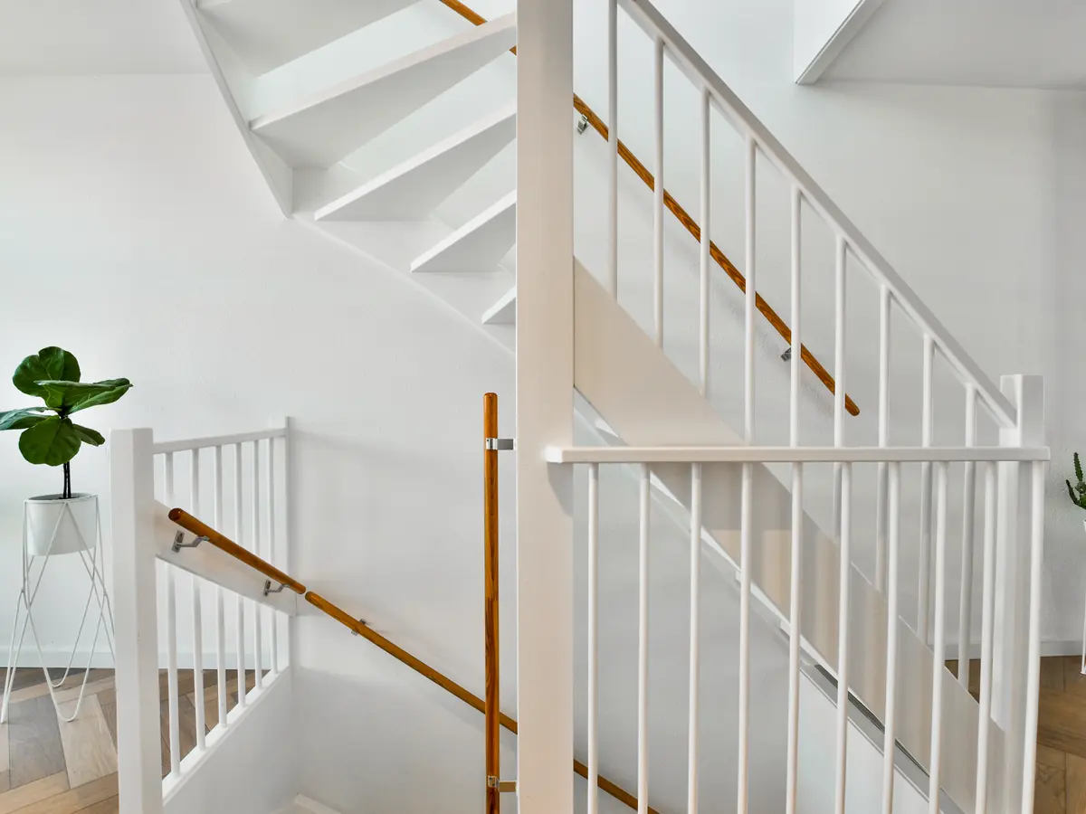 White staircase and railings in a bright hallway with plants