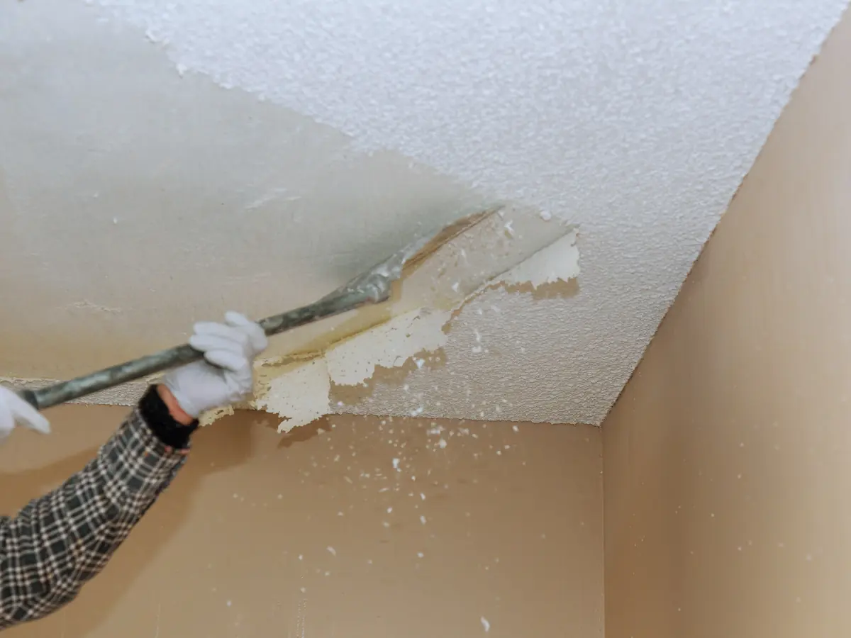 Scraper removing old textured finish from a ceiling
